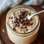 Blended cookie dough overnight oats in glass jar with gold spoon